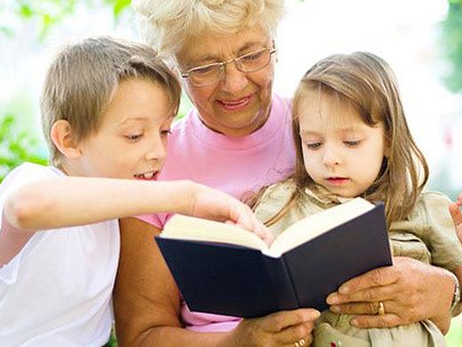 Dieses Bild zeigt eine ältere Dame die zwei Kindern aus einem Buch vorliest.
