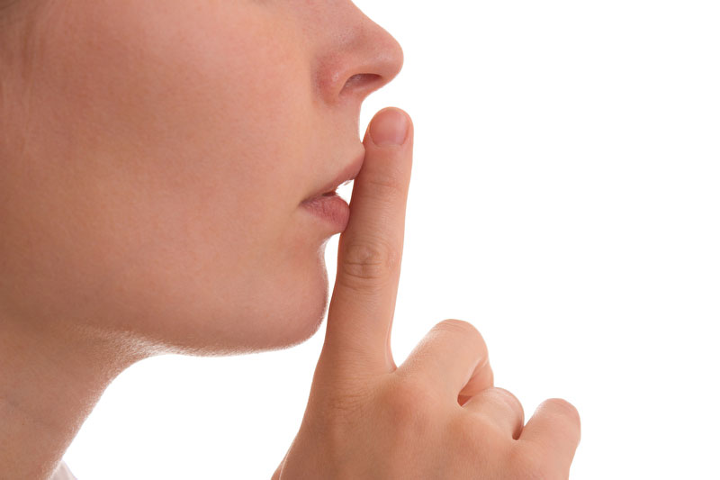 Dieses Foto zeigt einen Mund vor auf den ein Finger, als Zeichen der stille gehalten wird.