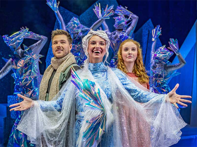 Das Bild zeigt drei Darsteller des Musicals Schneekönigin in glitzernden Kostümen.